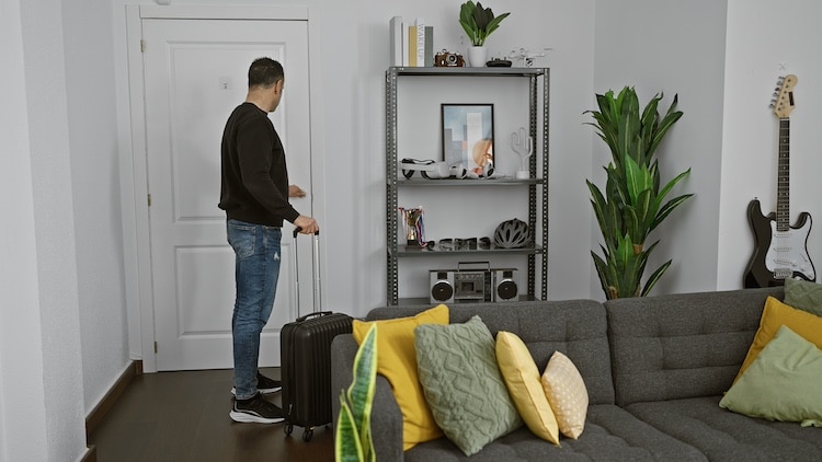 una persona con una valigia entra in casa