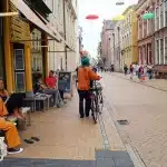 Via urbana con negozi, servizi e persone che camminano in un quartiere vivace