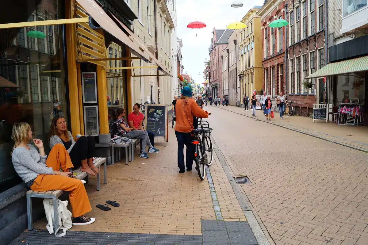 Via urbana con negozi, servizi e persone che camminano in un quartiere vivace