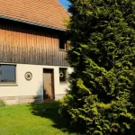 Mani che tengono una chiave davanti a una casa indipendente con giardino privato in campagna