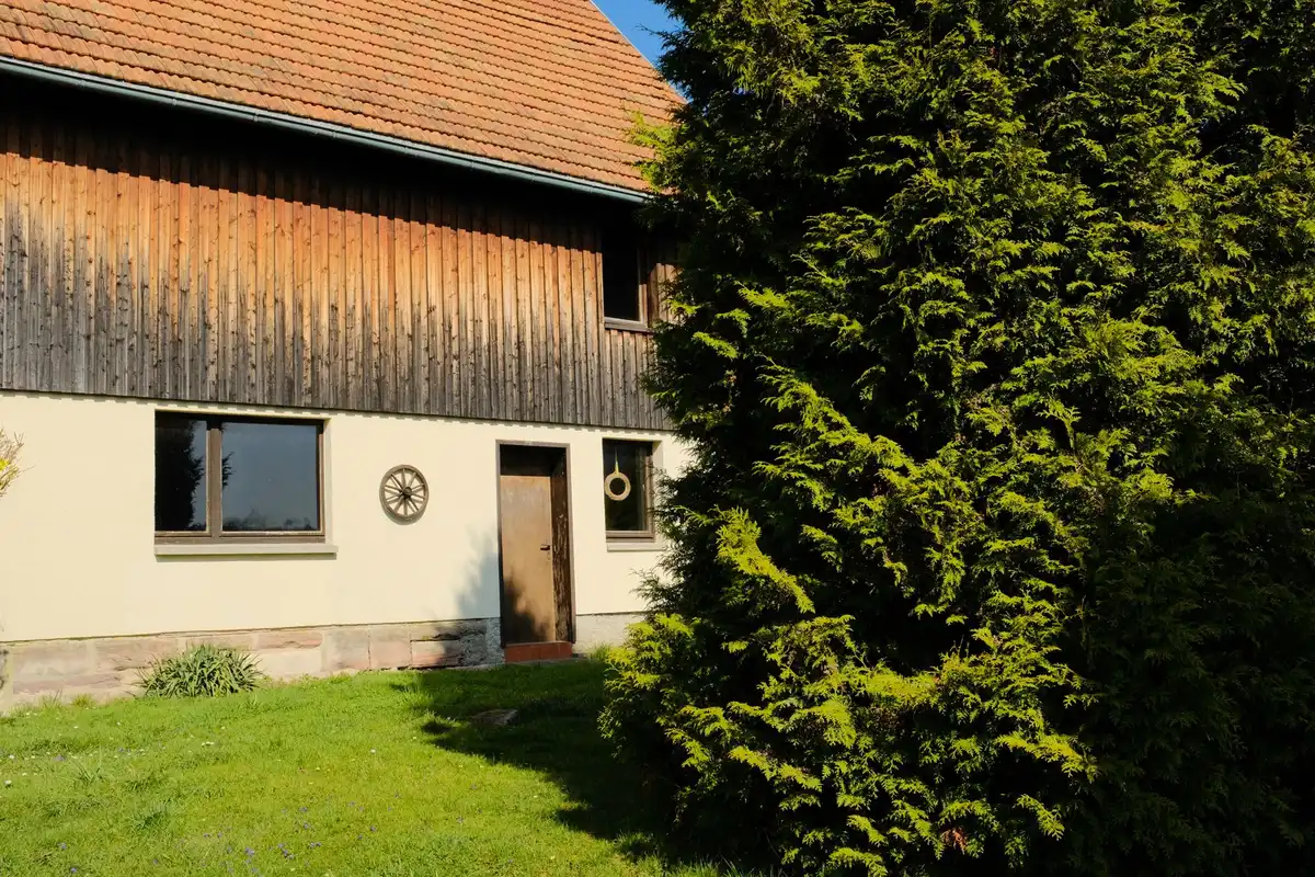 Mani che tengono una chiave davanti a una casa indipendente con giardino privato in campagna