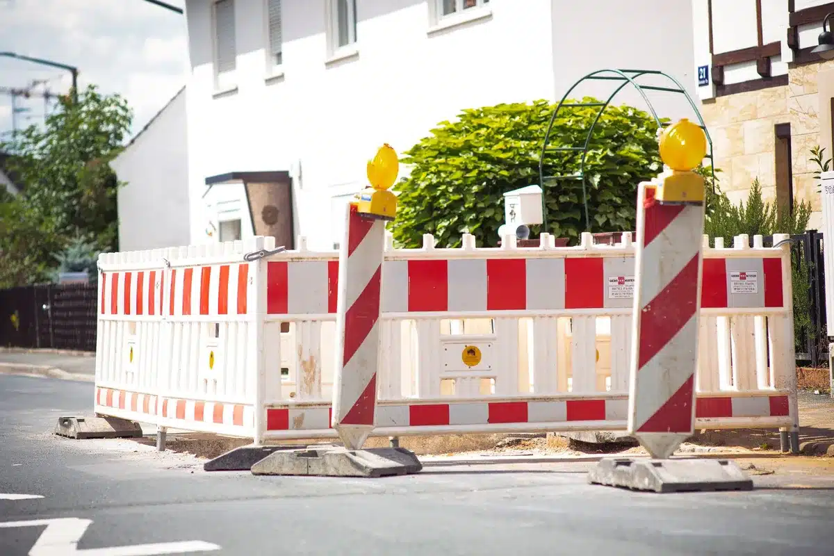 Cantiere stradale con recinzioni, barriere arancioni e segnaletica di deviazione del traffico in città