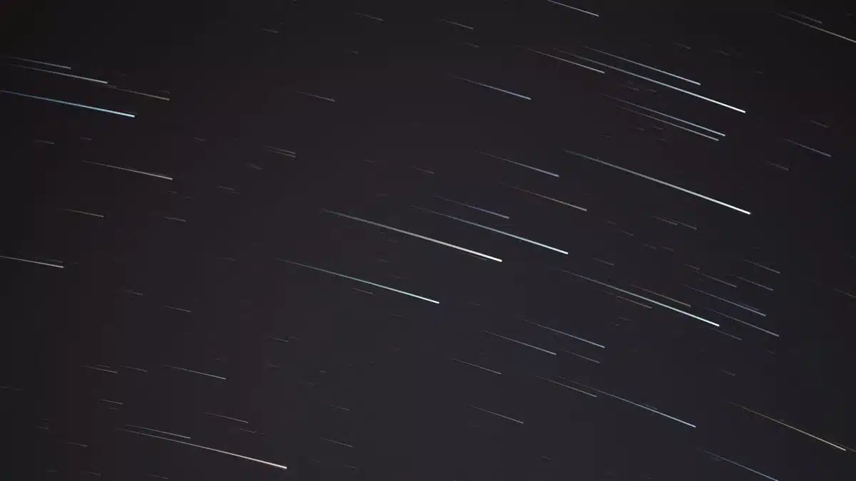 Pioggia di stelle cadenti che attraversa il cielo notturno scuro