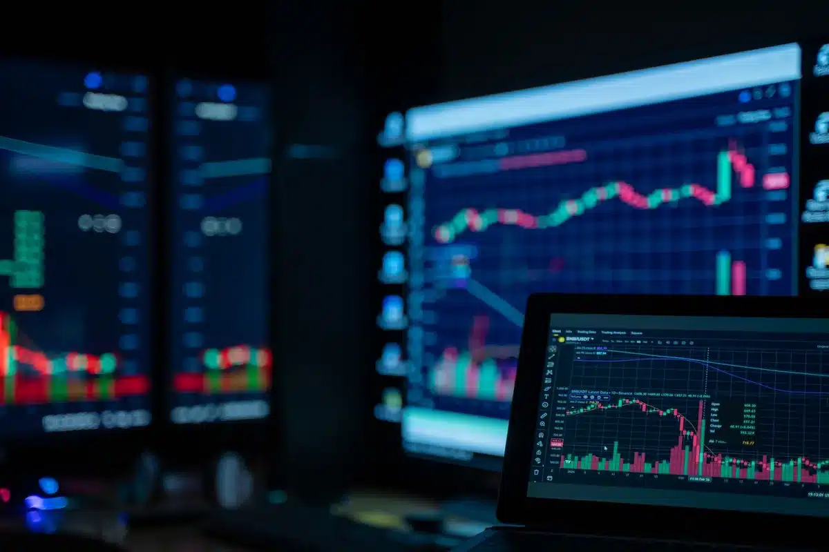 Schermi con grafici di cambio valutario e dati di mercato in tempo reale su una scrivania di trading
