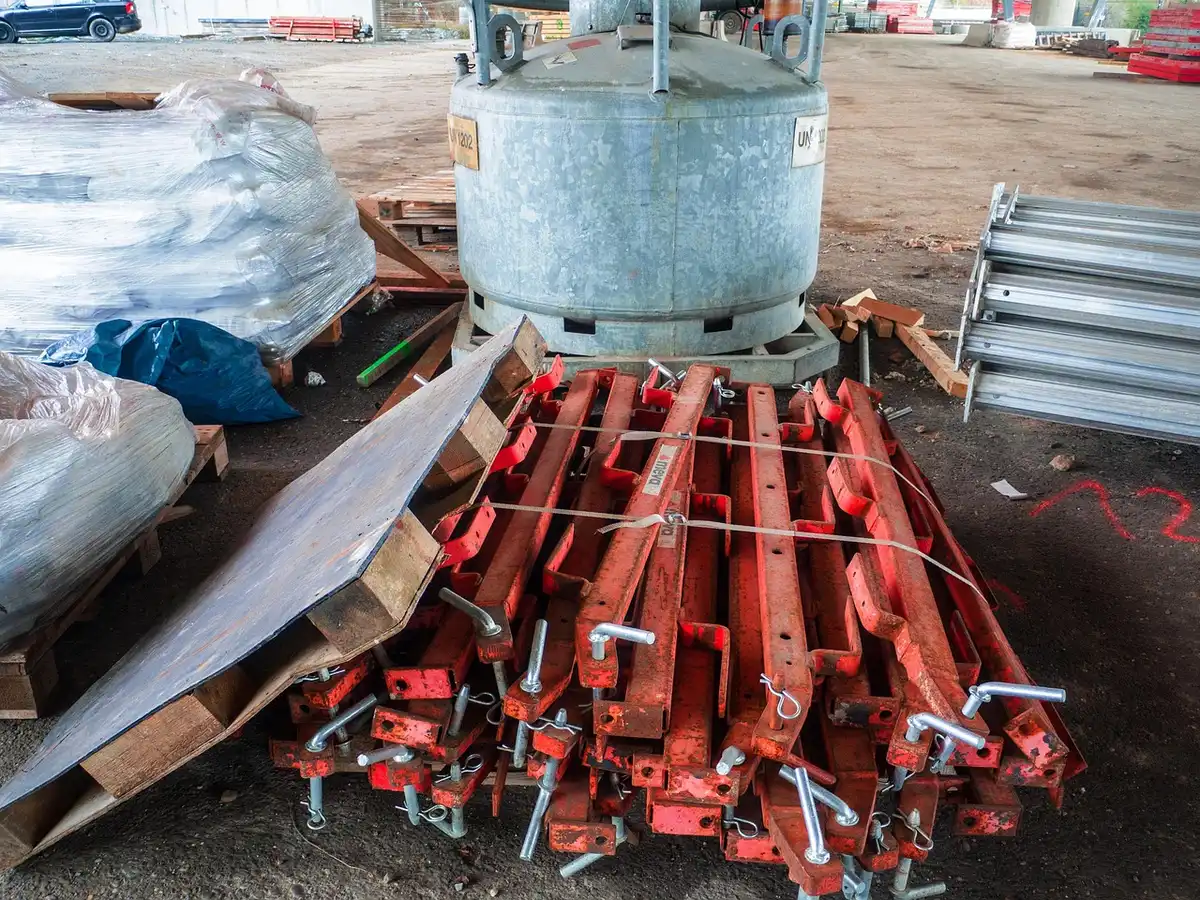 Cantiere anonimo con impalcature e materiali, operai in ombra