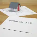 Mano anonima che porge chiavi su un tavolo con contratto e calcolatrice