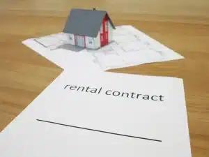 Mano anonima che porge chiavi su un tavolo con contratto e calcolatrice