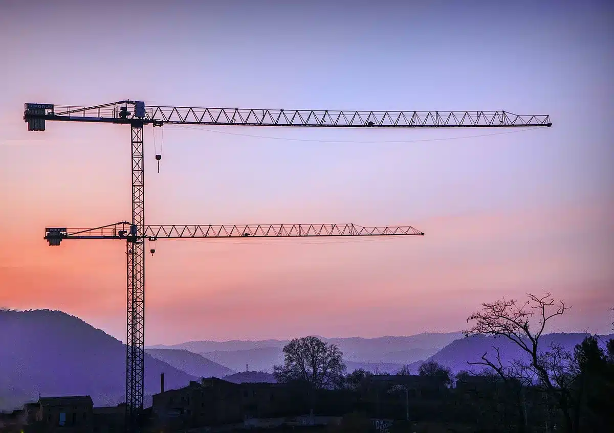 Cantiere edile con gru ferme e recinzioni, simbolo di progetti rallentati